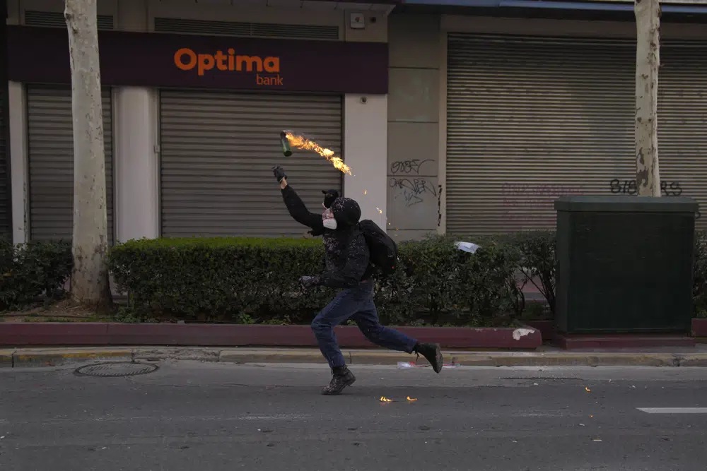 A protestor throws a cocktail molotov to the riot police during a 24-hours general strike in central Athens, on Thursday, March 16, 2023. Strikes by labor unions in Greece following a rail disaster last month have disrupted public transport and extensively disrupted services, with protests in cities across Greece planned later Thursday. (AP Photo/Petros Giannakouris)