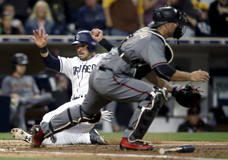 San Diego Padres' Austin Hedges, left, scores as the throw to Arizona Diamondbacks catcher Chris Iannetta is late, on a two-run double by Erick Aybar during the fifth inning of a baseball game in San Diego, Thursday, April 20, 2017. (AP Photo/Alex Gallardo)