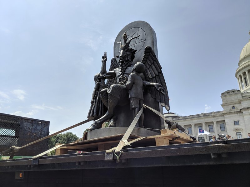 The Satanic Temple unveils its statue of Baphomet, a winged-goat creature, at a rally for the first amendment in Little Rock, Ark., Thursday, Aug. 16, 2018. The Satanic Temple wants to install the statue on Capitol grounds as a symbol for religious freedom after a monument of the Biblical Ten Commandments was installed in 2017. (AP Photo/Hannah Grabenstein)