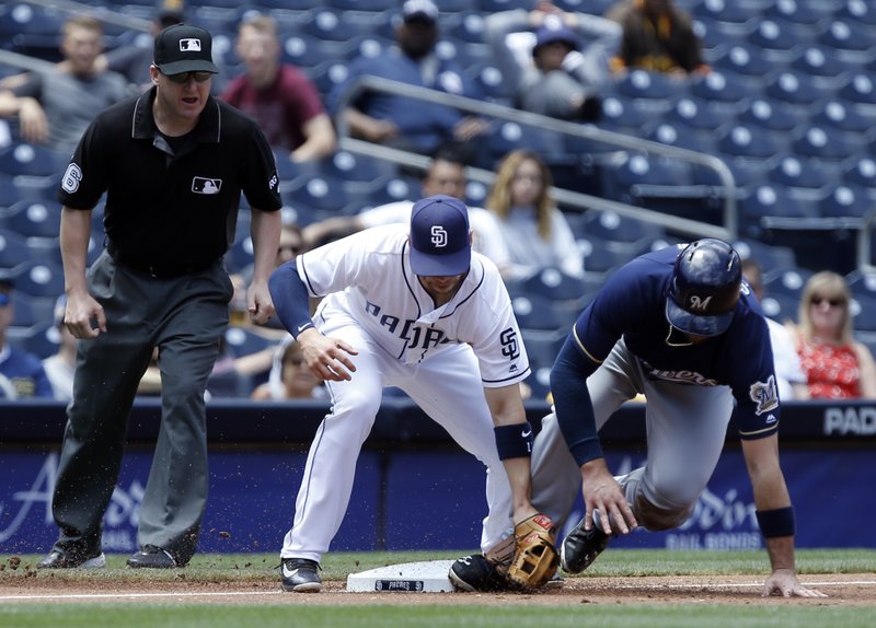 Milwaukee Brewers' Travis Shaw, right, beats the throw to San Diego Padres third baseman Ryan Schimpf on a wild pitch as umpire Ryan Blakney, left, watches to make the call during the second inning of a baseball game in San Diego, Thursday, May 18, 2017. (AP Photo/Alex Gallardo)