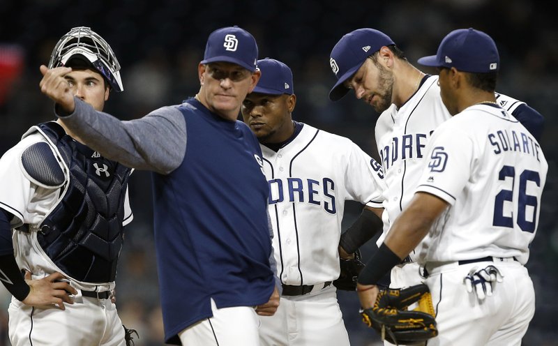 San Diego Padres pitching coach Darren Balsley, second from left, calls out the trainer to check on an injury to starting pitcher Jarred Cosart, second from right, with catcher Austin Hedges, left, shortstop Erick Aybar, center, and second baseman Yangervis Solarte watching during the fourth inning of a baseball game against the Arizona Diamondbacks in San Diego, Tuesday, April 18, 2017. Cosart did not continue to pitch in the game. (AP Photo/Alex Gallardo)