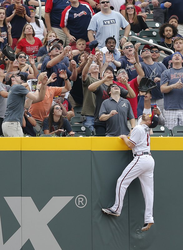 Atlanta Braves' center fielder Ender Inciarte (11) goes up the wall as fans reach for a ball ht for a home run by San Diego Padres' Ryan Schimpf in the second inning of a baseball game Sunday, April 16, 2017, in Atlanta. (AP Photo/John Bazemore)