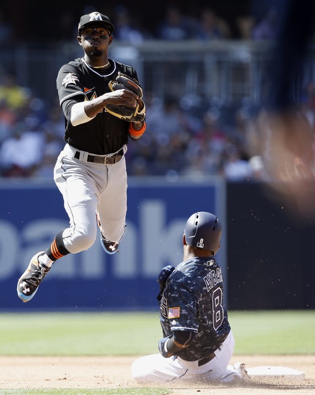 Miami Marlins second baseman Dee Gordon, left, leaps away from the forced out San Diego Padres' Erick Aybar (8), then throws to first to get Wil Myers for a double play during the fifth inning of a baseball game in San Diego, Sunday, April 23, 2017. (AP Photo/Alex Gallardo)