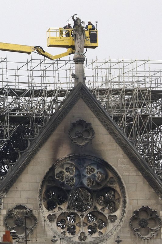 Experts prepare to lift a statue from the damaged Notre Dame cathedral after the fire in Paris, Tuesday. (Credit: Kamil Zihnioglu/AP.)