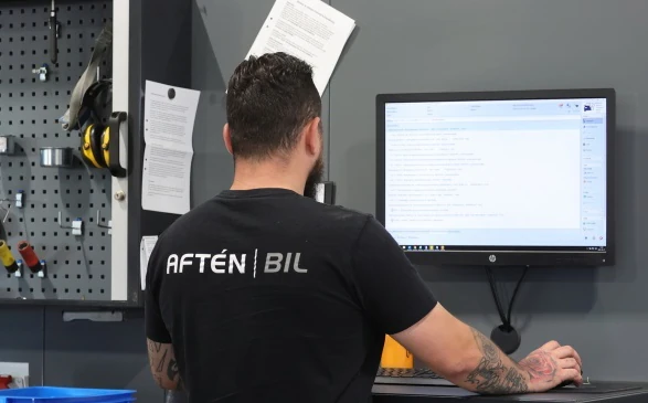 Aftén Bil-mekaniker arbetar vid en dator i verkstaden