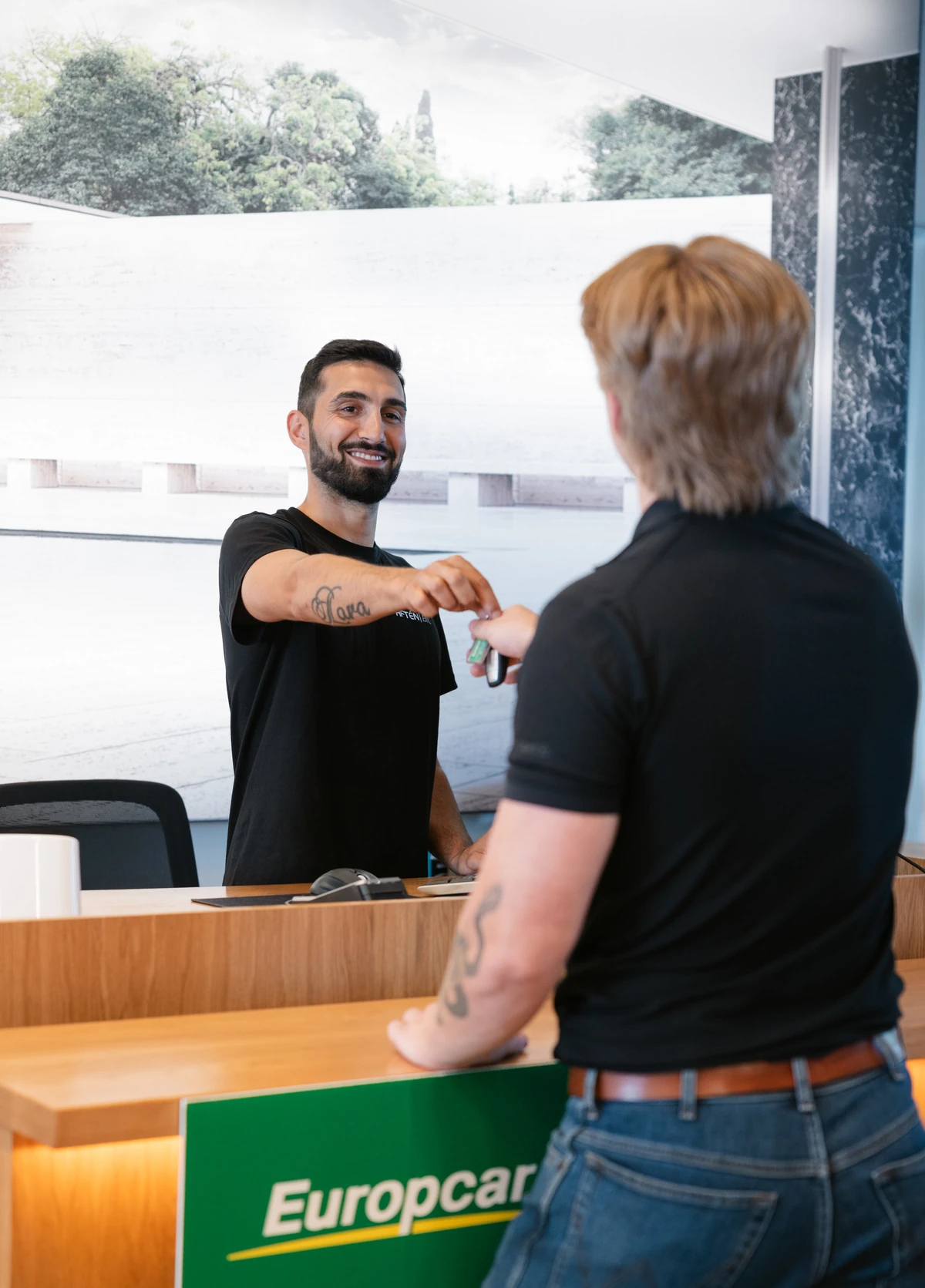 Säljare lämnar över nycklar till kund vid hyrbilsreceptionen