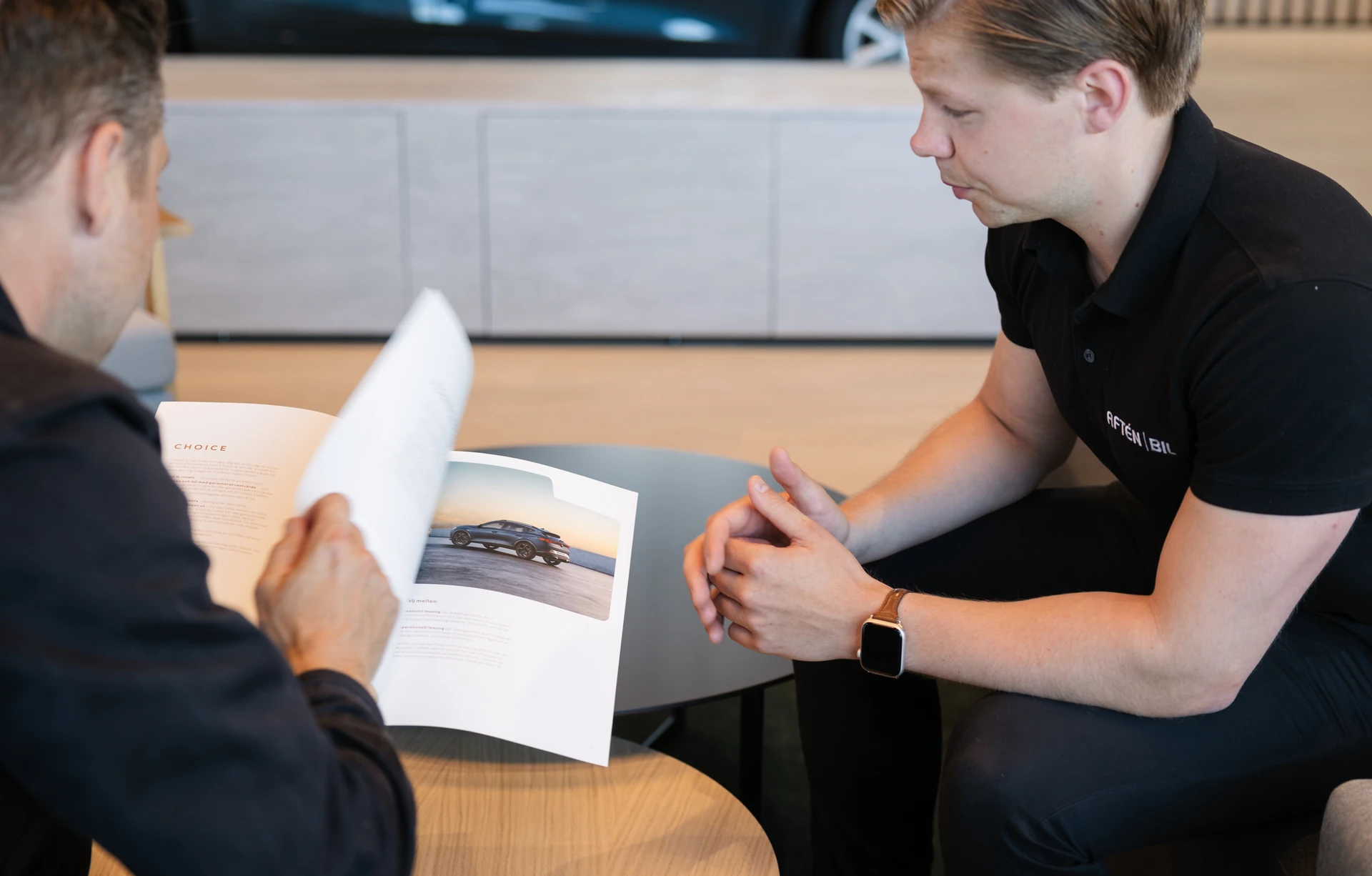 Säljare och kund på Aftén Bil tittar igenom produktkatalog