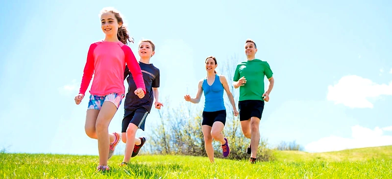Familie løber glad i græsset. Perfekt til Junglerun Fyn!