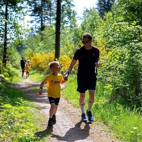Far og søn løber glad i skoven. Junglerun Holstebro.
