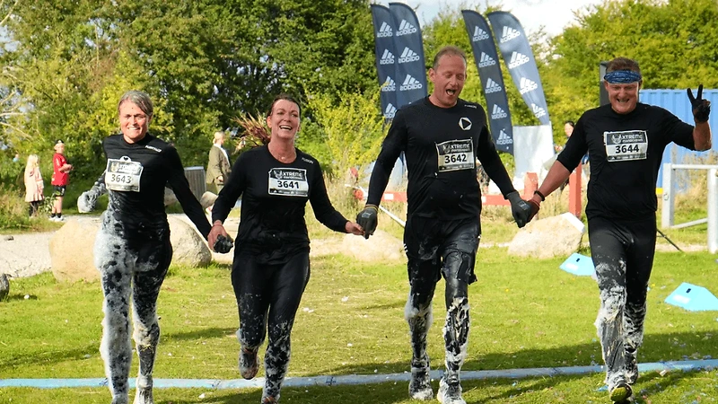 Mud Race Aarhus 2025 deltagere løber gennem mudderet og ser glade ud.