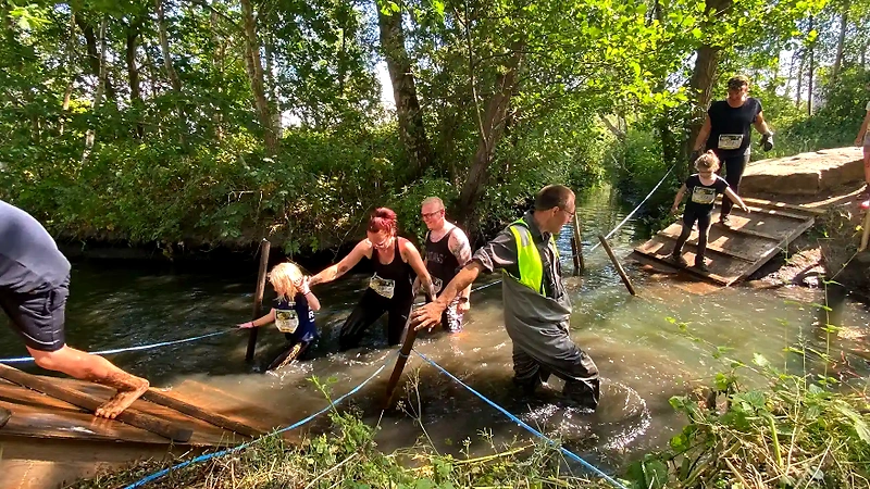 Kvinder vander gennem en strøm under Ladies Mud Race. Udfordrende terræn!