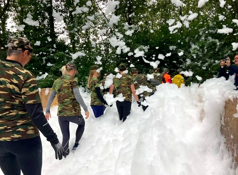 Kvinder i camouflage løber gennem skum under Ladies Mud Race.