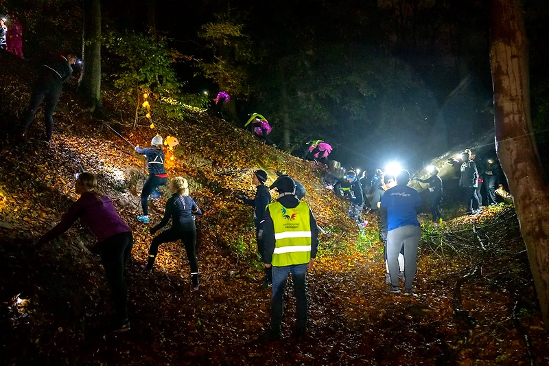 Natløb i mudder med hovedlamper. Deltagerne navigerer en mørk og udfordrende bane.