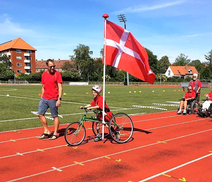 Ung atlet i kørestol deltager i løb. Positivt og inkluderende billede.