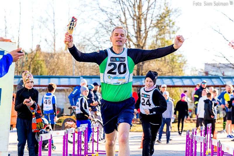 Runners compete, one man with a torch. Kids' race and street run.