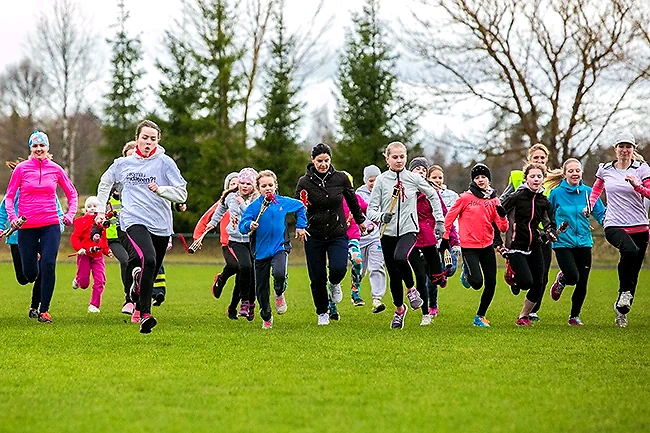 Young runners are running on the grass.