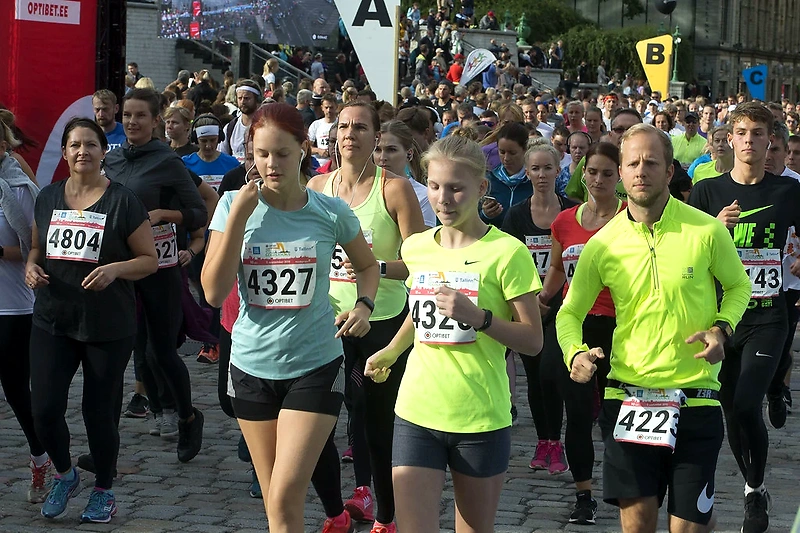 Runners at the starting line, bib numbers visible, crowded.