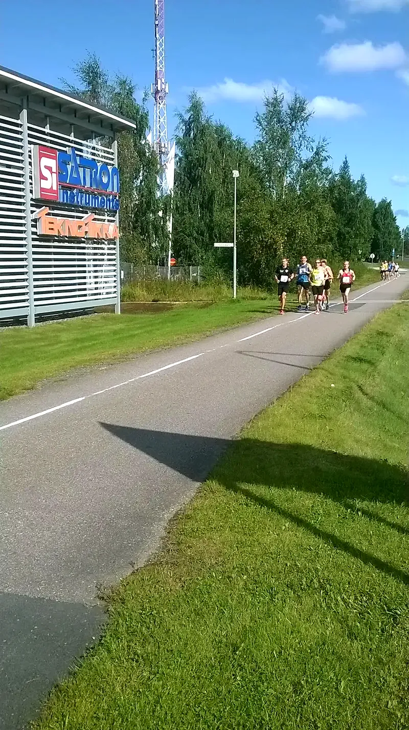 Juoksijoita juoksemassa maantiellä aurinkoisena päivänä.