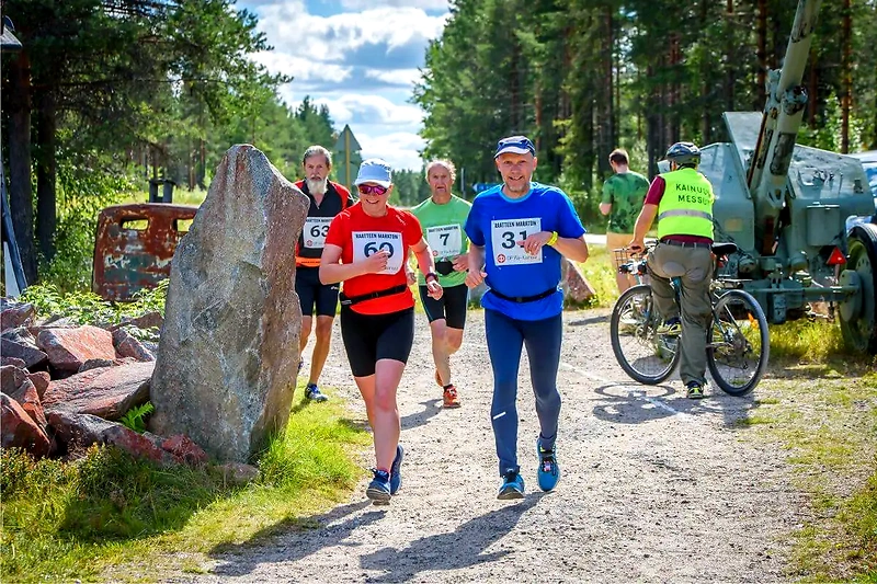 Juoksijoita Raatteen Maratonilla, taustalla muistomerkkejä.