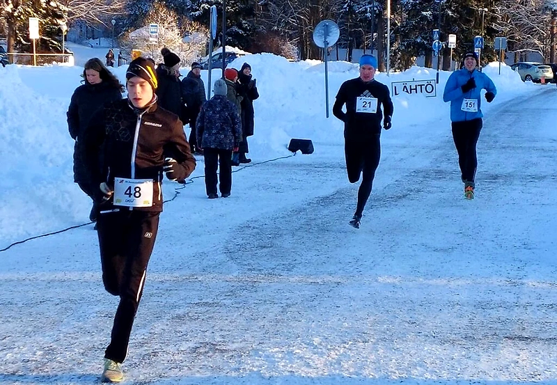 Talvinen juoksukilpailu, jossa juoksijat juoksevat lumisella tiellä.