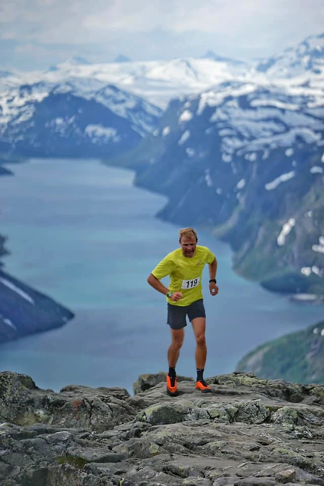 Løper på en fjellsti med vakker natur i bakgrunnen.