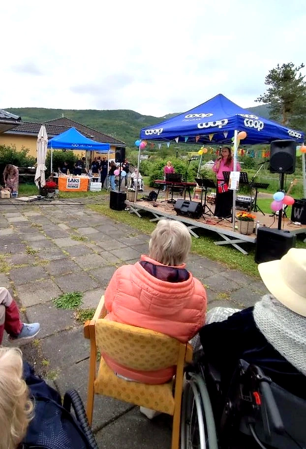 A scene with an artist performing at a festival. People are sitting and watching.