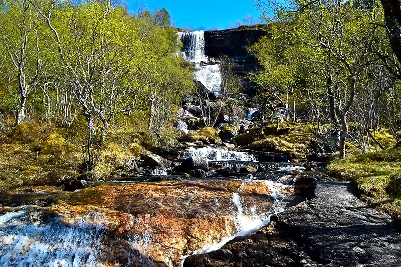 Waterfall in Bodøryggen. Scenic trail with waterfalls, trees, and stones.