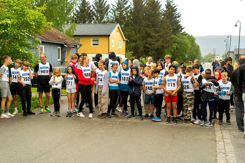 Children and adults ready for the race, with bib numbers and sponsor logos.