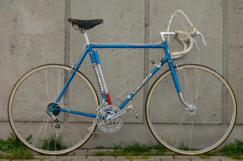 Blue road bike against a concrete wall, ready for the race.