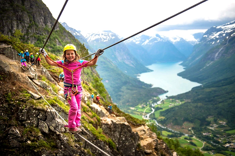 Girl on a mountain trail with a zipline over a lake, ready for Crazy Race.