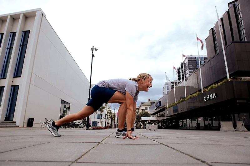 Runner in the starting position. The buildings in the background suggest the race is in an urban environment.
