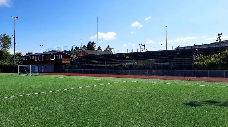 Athletics track with a running track and bleachers on a sunny day.