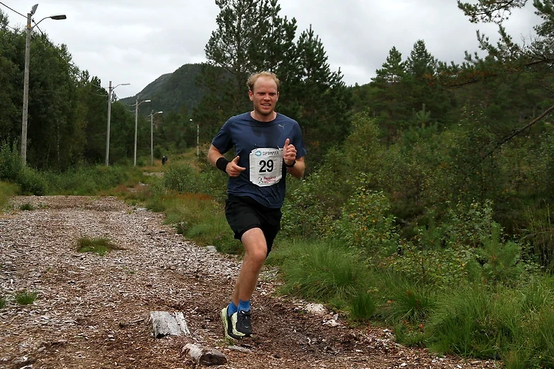 Løper i terrengløp med startnummer 29. Løypa går på grus og sti med skog i bakgrunnen.