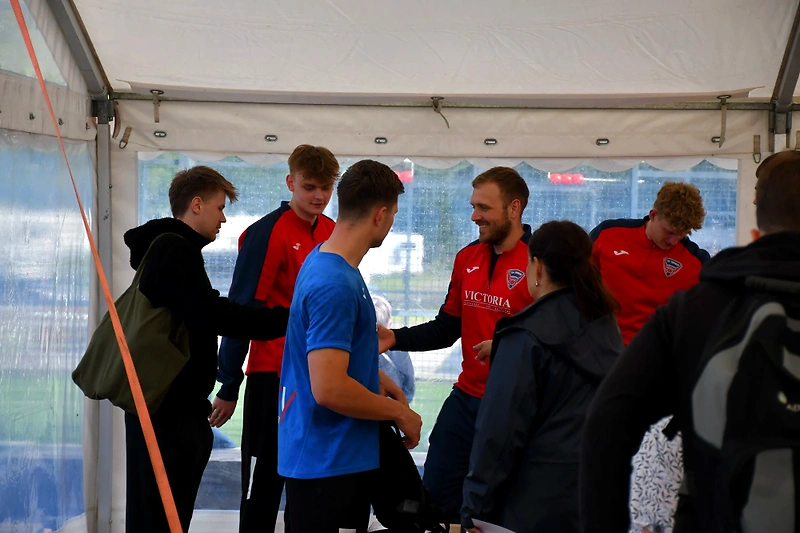 A group of people in sportswear under a tent, possibly before a race.