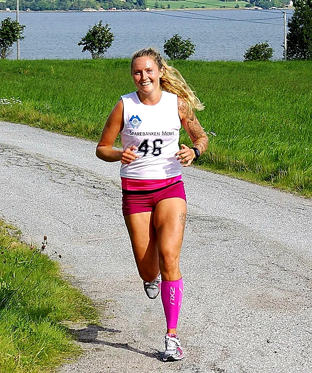 A female runner in the Flemstubben race, wearing bib number 46, pink shorts and socks, on a gravel road.