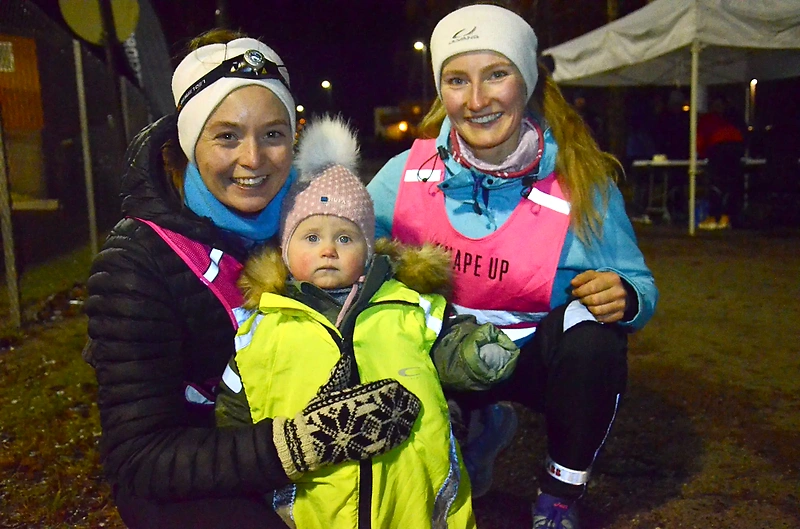 Runners with children in reflective vests, possibly a race or training in the dark.