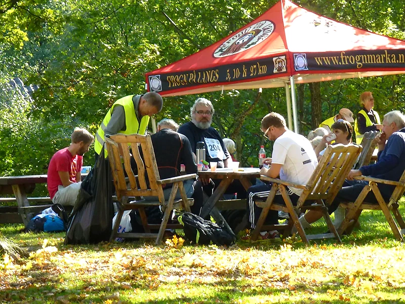 Participants at the Frogn long race are sitting around a table. A tent with the race's name is in the background.