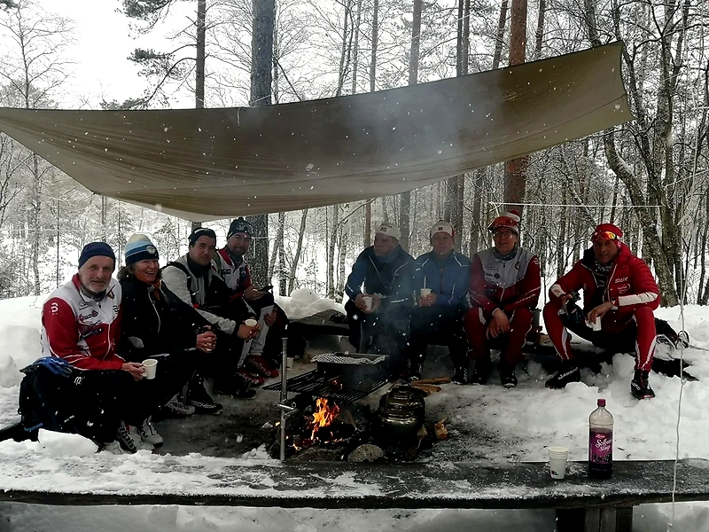 People around a campfire in a snow-covered forest.