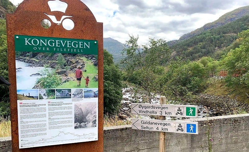 Signs for Kongevegen and Galdanevegen. Shows the route in Lærdal, and people walking.