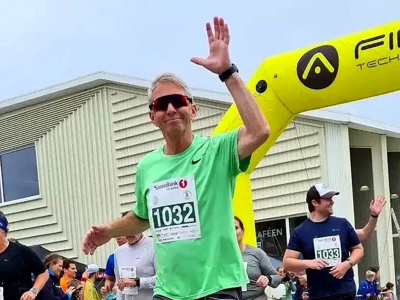Runners at the finish line of a race, with bib numbers and the finish arch.