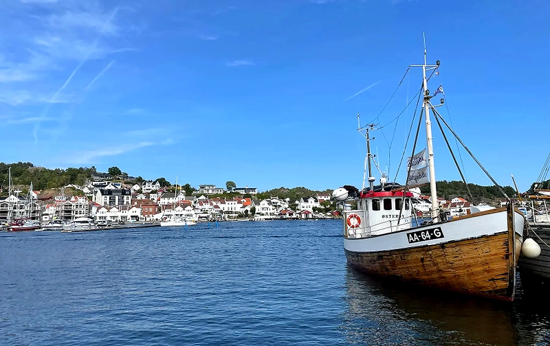 Boats in Grimstad harbor, with white houses in the background.