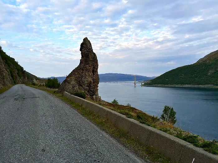 Road along the coast with mountains and a bridge in the background, possibly part of the route for the Hammerfest Mile.