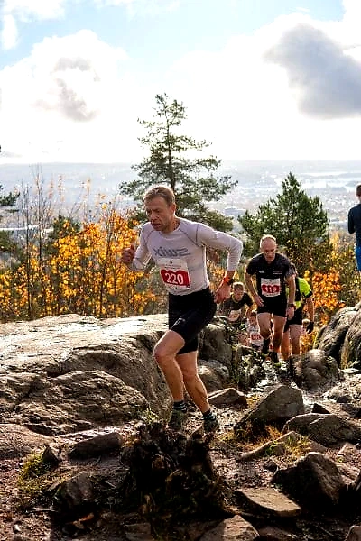 Runners in cross-country running in Nordmarka, with race numbers and nature.
