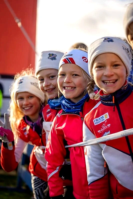 Children in the starting area for a cross-country race, ready to run and smiling.