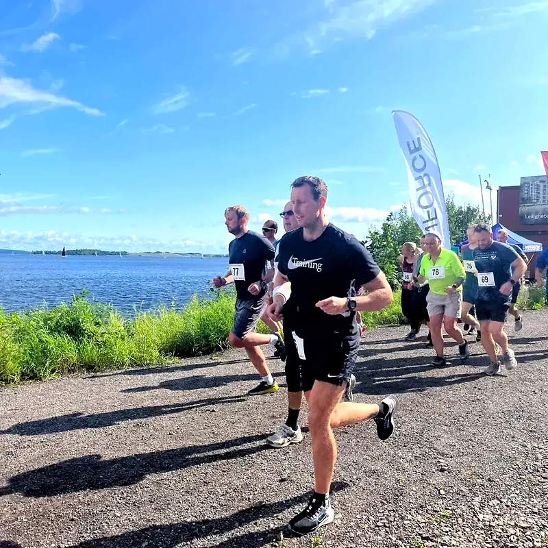 Runners in the Angers Klev Opp trail race along the lake, on a sunny day.
