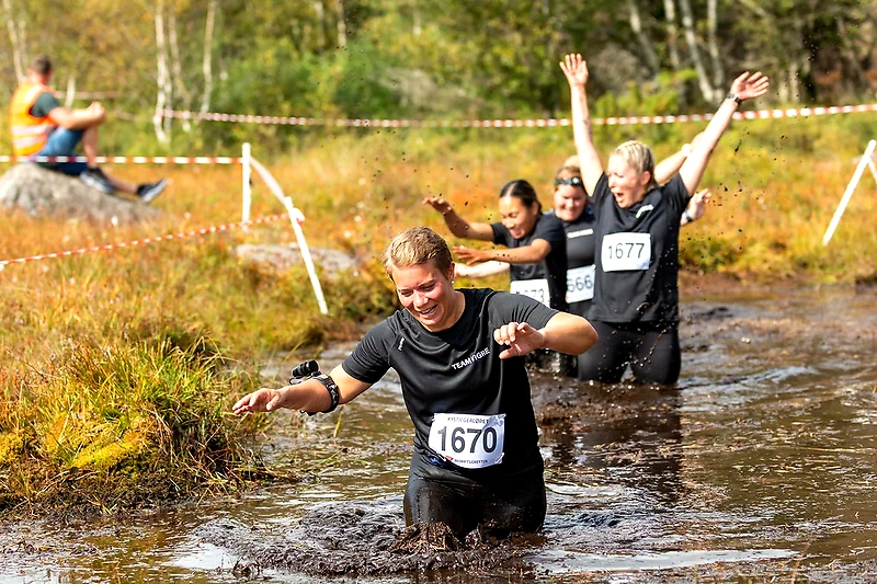 Participants in the Coastal Hunter Race cross a muddy obstacle.