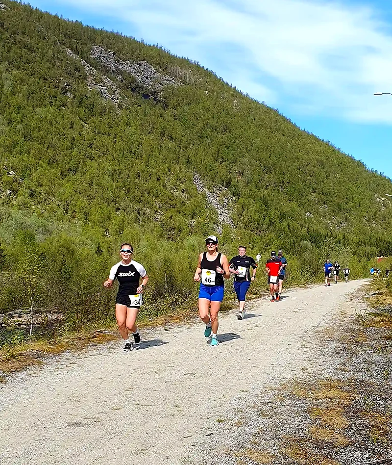 Løpere på grusvei i et fjellandskap, trolig under et løp.