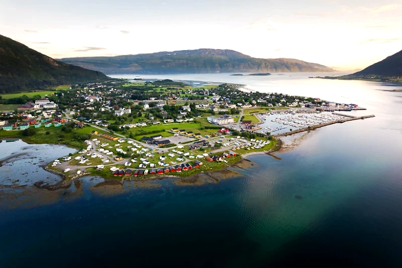 Overview image of Nesna village by the sea, with mountains in the background.