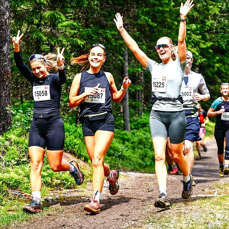 Runners in cross country with bib numbers and smiles.