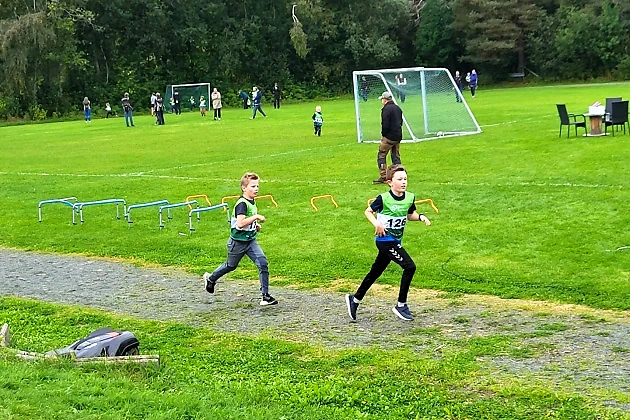 Children's race on a grass track with obstacles. Two boys are running.